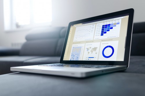 A laptop on a couch showing various graphs